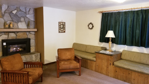 A comfortable living room with two day couches, and two chairs in front of a gas fireplace.