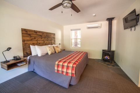 A studio cabin with a gas fireplace. This cabin also has an A/C heater unit in it. A wall mounted TV is at the foot of the king bed.