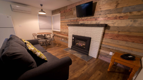 A pull out couch in front of a gas fireplace with a wall mounted TV above it. The dining room table seats 4. There is an A/C heater unit in the cabin also.